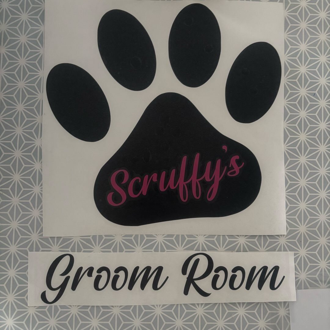 The Scruffy's Groom Room sign on the salon wall: a black paw print with Scruffy's in pink script inside it, and Groom Room on a plaque underneath.